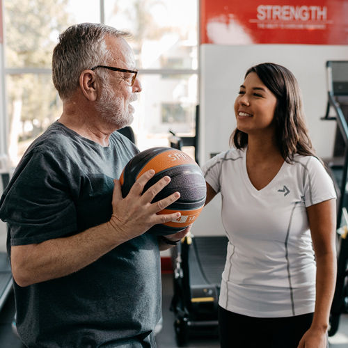 a personal trainer certified by ace fitness speaking with a patient holding a medicine ball